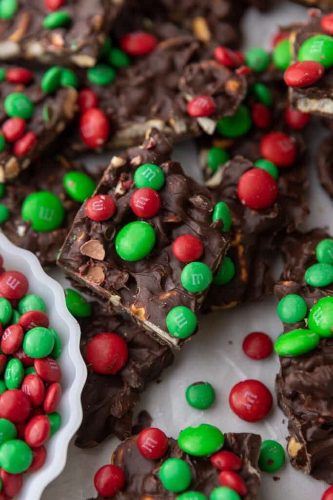 multiple christmas pretzel peanut m&m's bark in a pan with a bowl of M&M's next to it