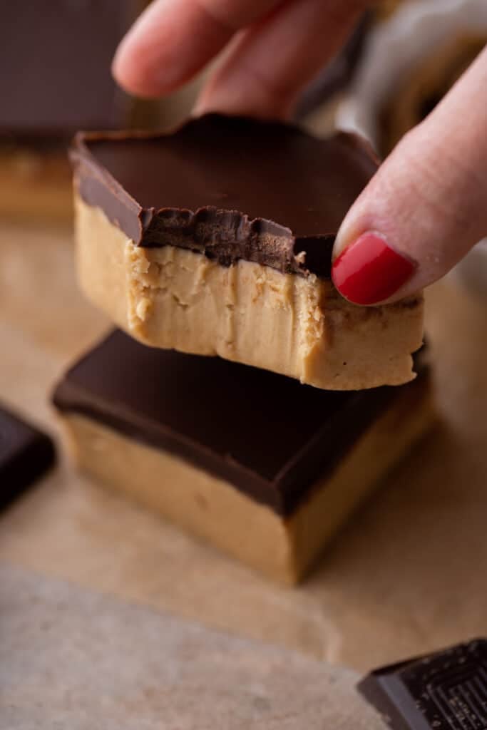 a square from the buckeye bars recipe with a bite take out of it being held up by a hand