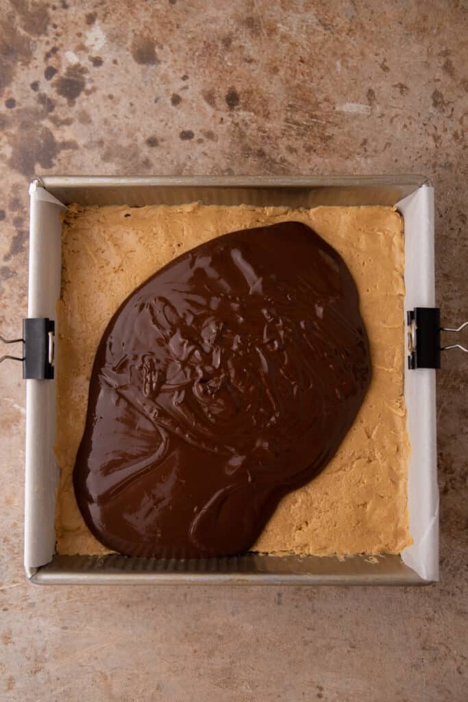 chocolate being spread over the peanut butter layer