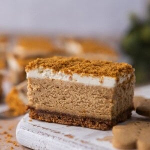 Close-up of a gingerbread cheesecake bar with creamy spiced filling, gingersnap crust, and crumb topping.โ