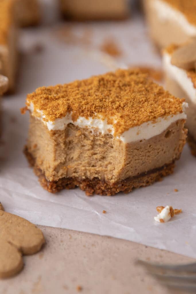 a single gingerbread cheesecake bar with a bite taken out of it