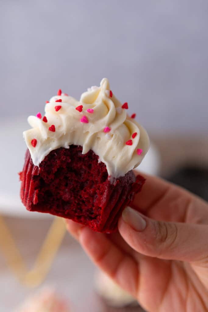 one of the small batch Red Velvet cupcakes with a bite taken out of it being held up by a hand