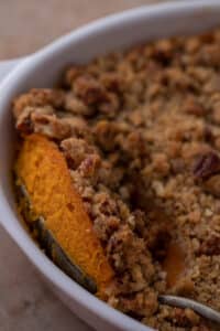 a spoon digging into a sweet potato casserole with pecans