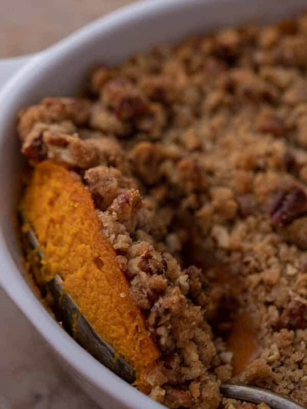 a spoon digging into a sweet potato casserole with pecans