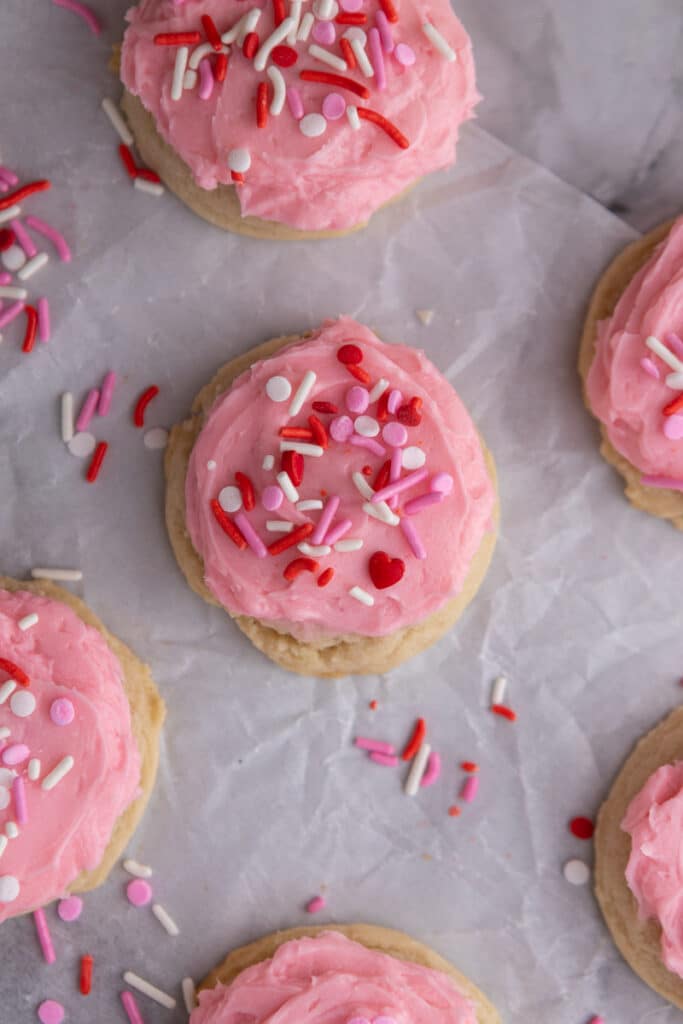 Overhead shot of frosted cookies with pink frosting and sprinkles