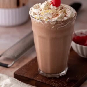 side view of the chocolate milkshake recipe with a blender behind it