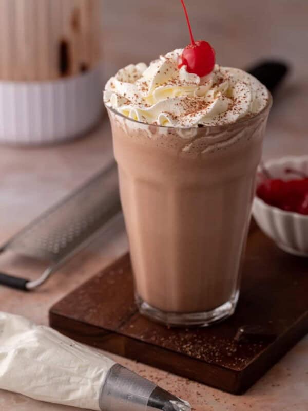 side view of the chocolate milkshake recipe with a blender behind it