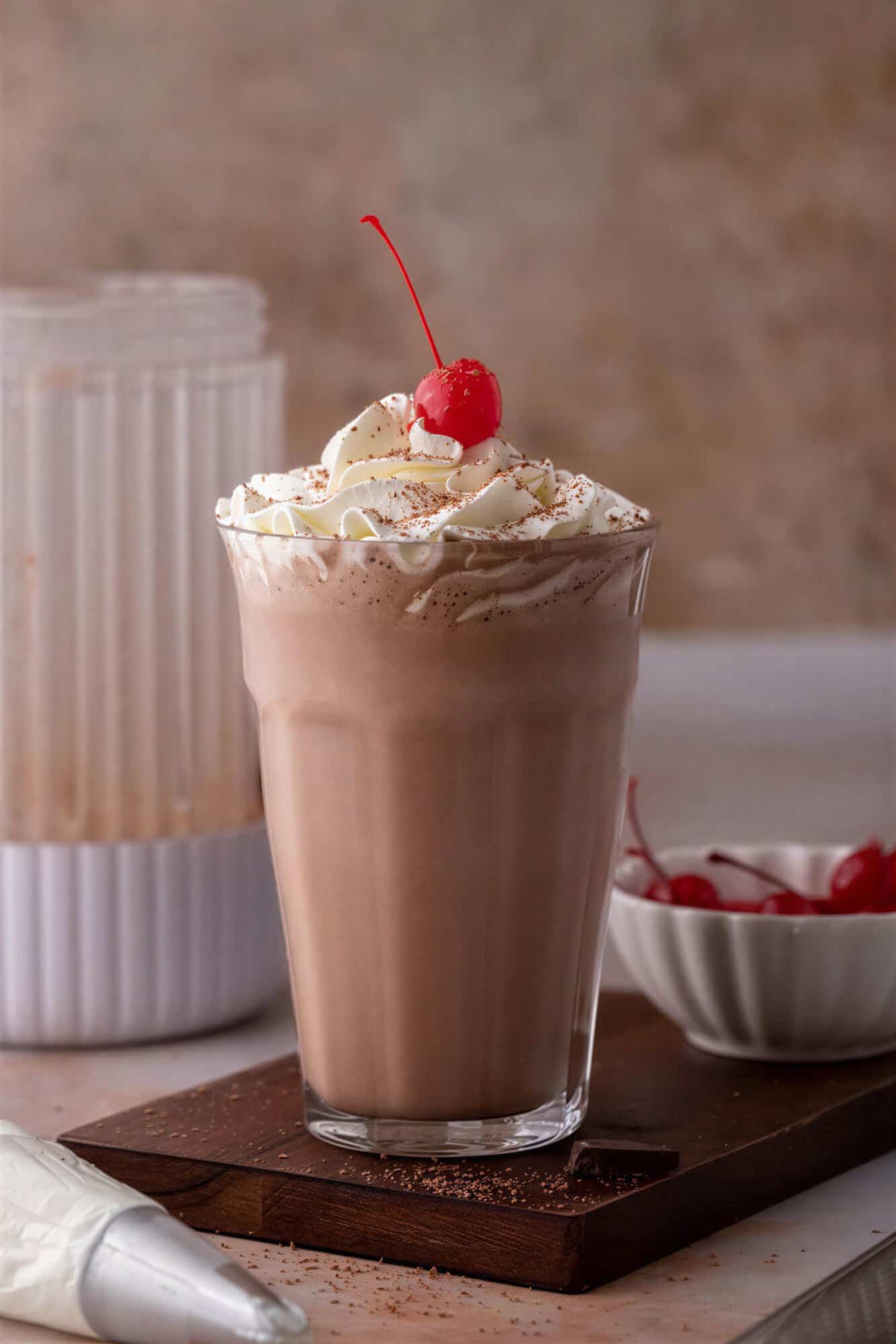 side view of the chocolate milkshake recipe with a blender behind it.