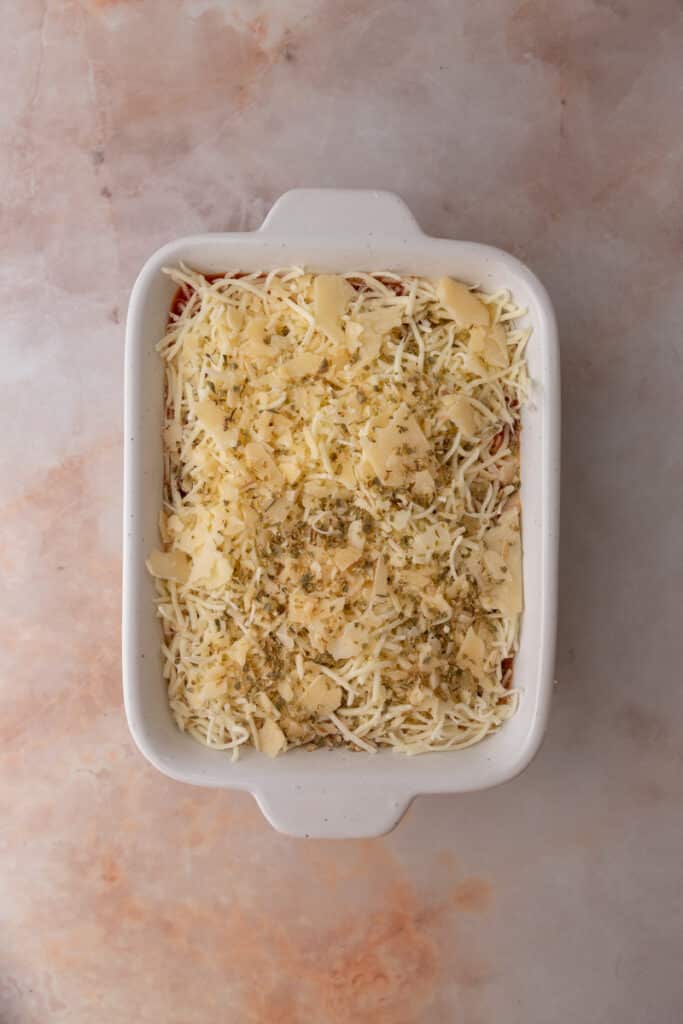 shredded cheese over the tomato sauce in a dish