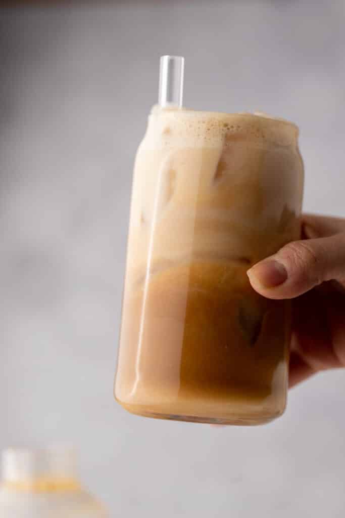an iced hazelnut oatmilk shaken espresso starbucks copycat being held up by a hand