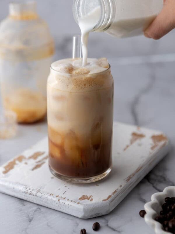 Pouring vanilla sweet cream into a homemade Starbucks cold brew for this Starbucks copycat recipes guide