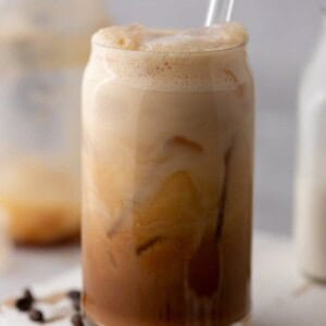 an iced hazelnut oatmilk shaken espresso starbucks drink in a glass with a straw
