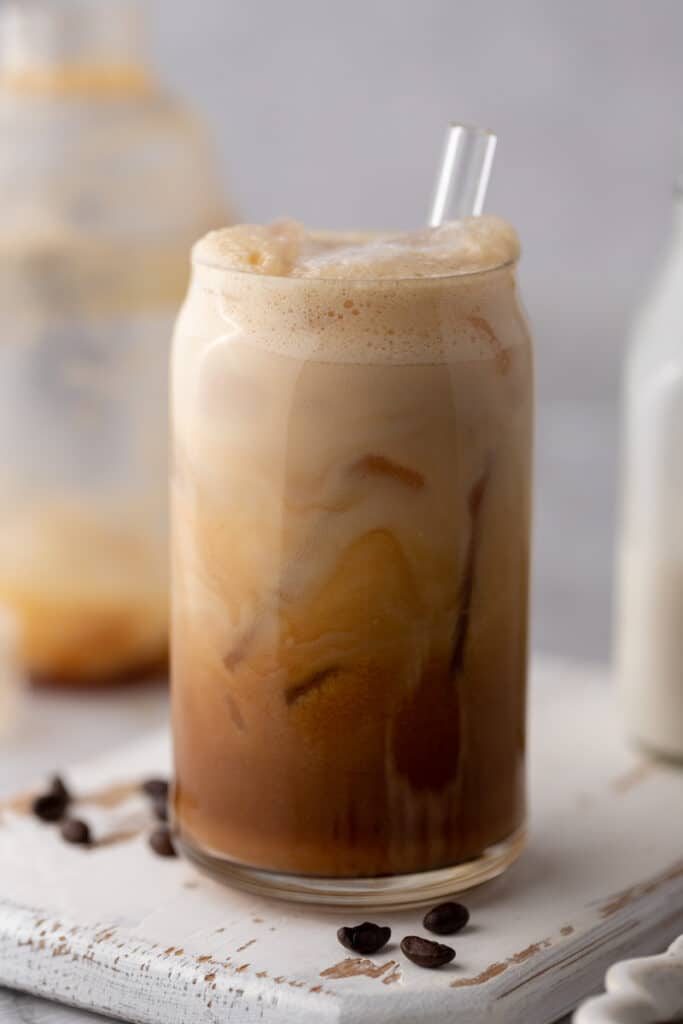 an iced hazelnut oatmilk shaken espresso starbucks drink in a glass with a straw