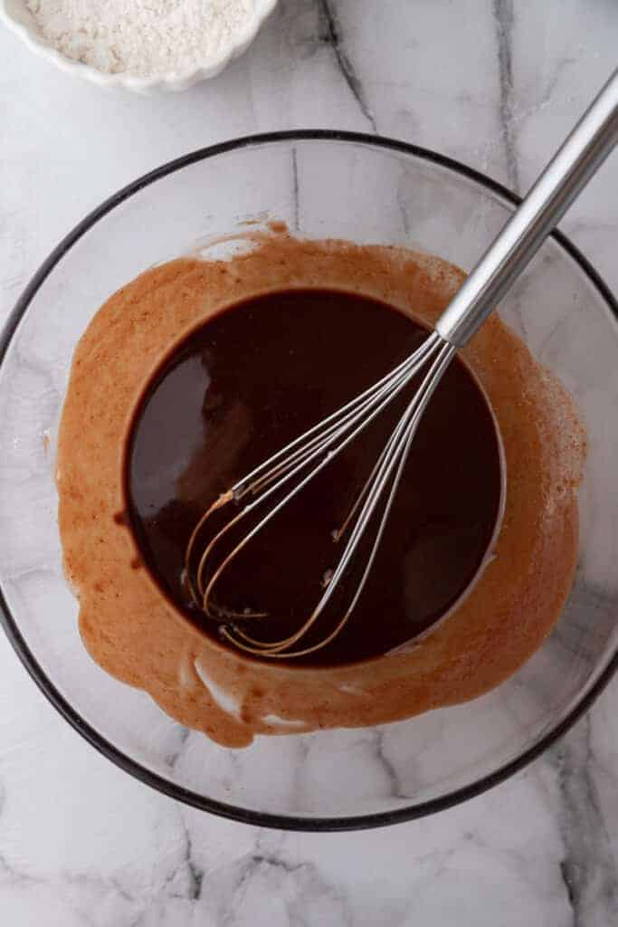 Melted butter and chopped chocolate whisked smooth in a glass bowl for Starbucks copycat brownies.