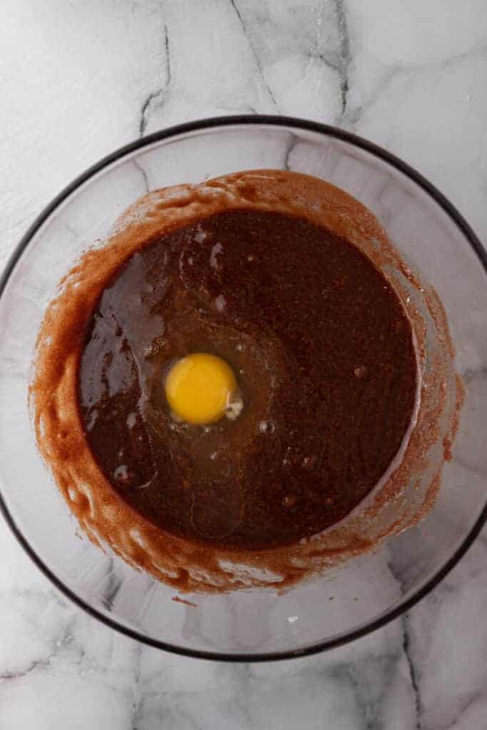 One egg added to the glossy chocolate and sugar mixture before whisking it in fully.