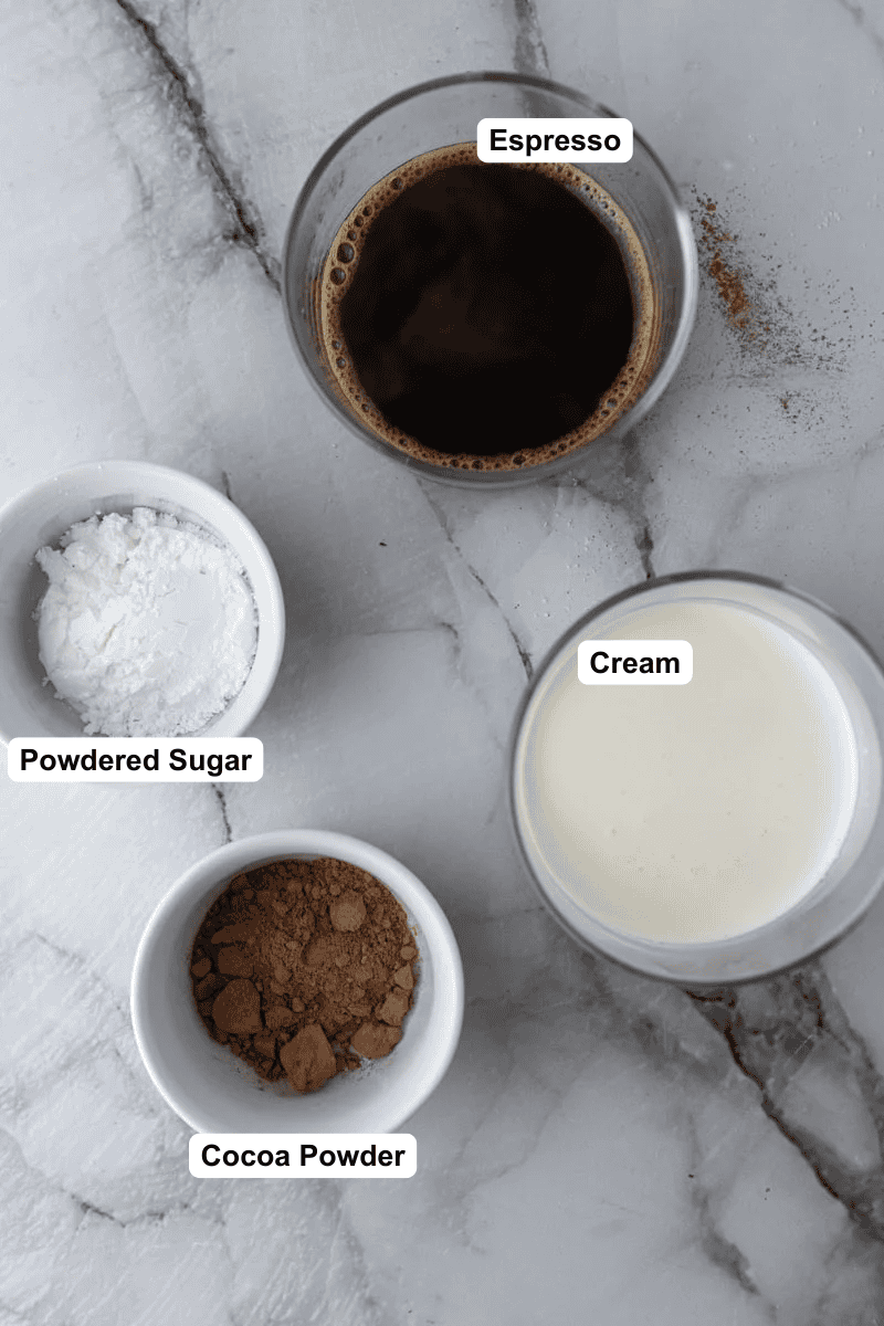 Einspanner coffee ingredients: a glass of espresso, powdered sugar, heavy cream, and cocoa powder.