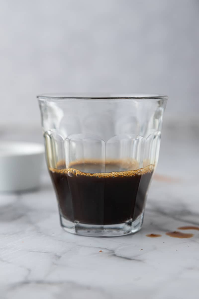 Double shot of espresso in a small clear glass.