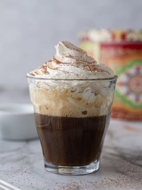 espresso and whipped cream with cocoa powder in a glass cup