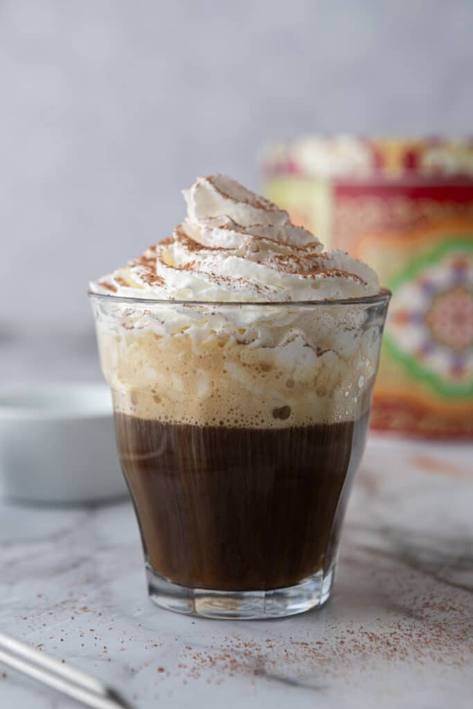 espresso and whipped cream with cocoa powder in a glass cup