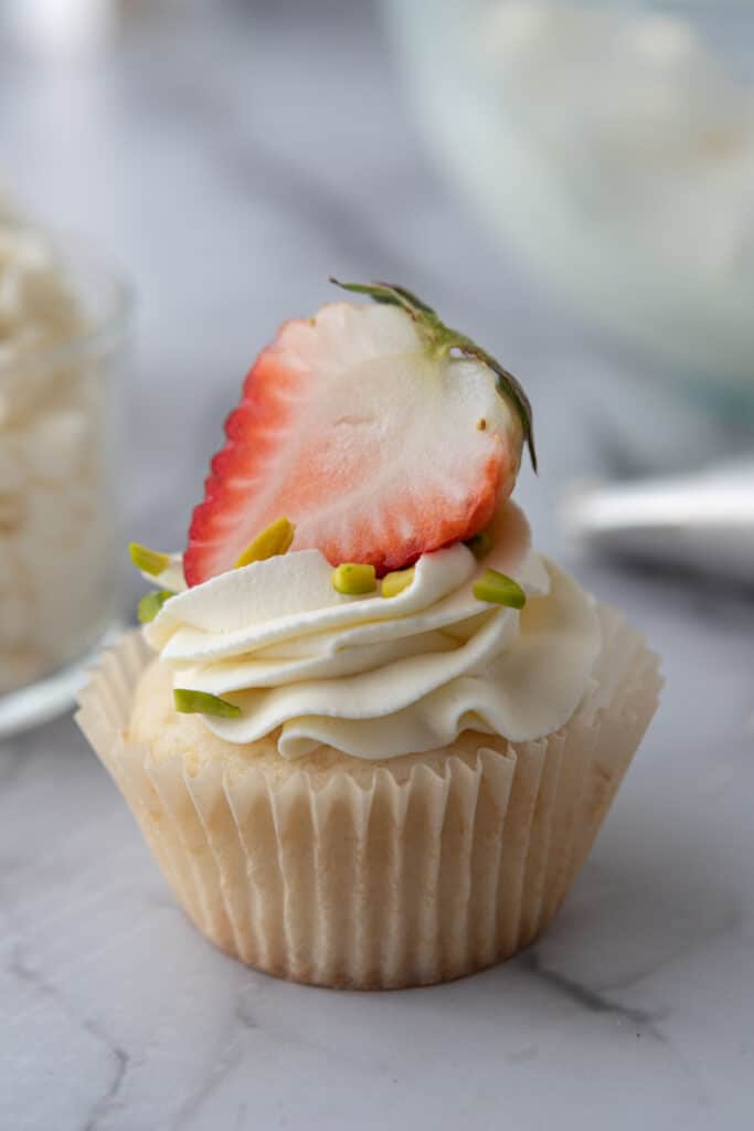 mascarpone cake frosting recipe on a cupcake with a strawberry on top