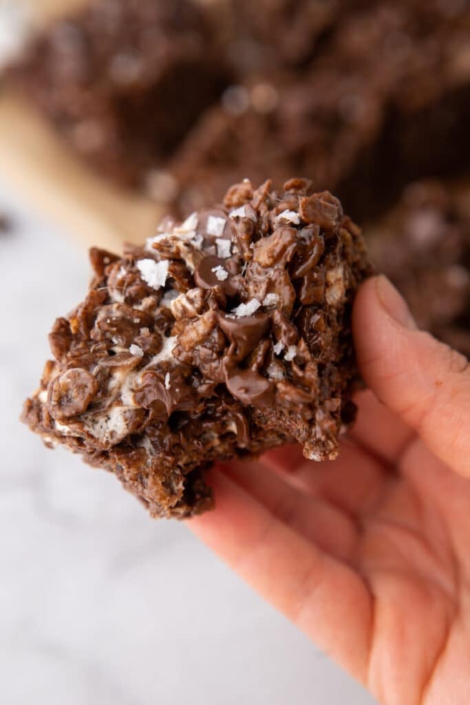 a hand holding up a square of the brown butter chocolate rice krispies treats