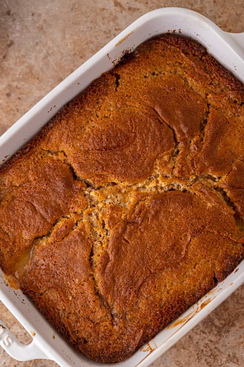 Baked old fashioned peach cobbler with a golden brown top in a baking dish.