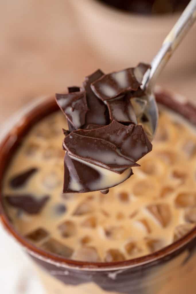 Spoon holding shreds of cracked chocolate