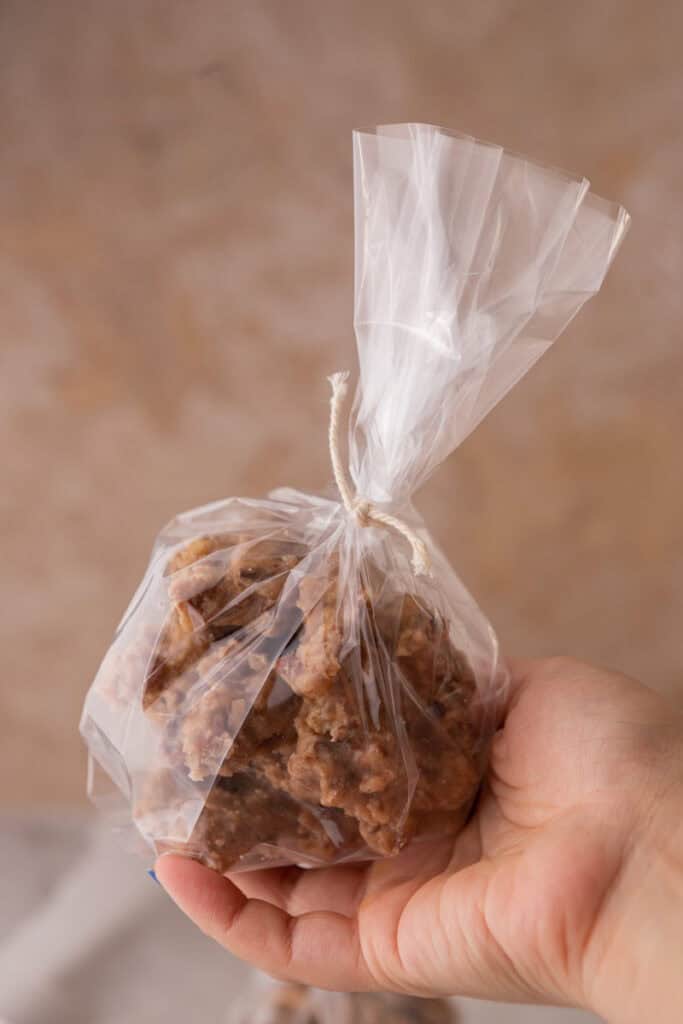 New Orleans pecan pralines recipe wrapped up in a bag being held up by a hand