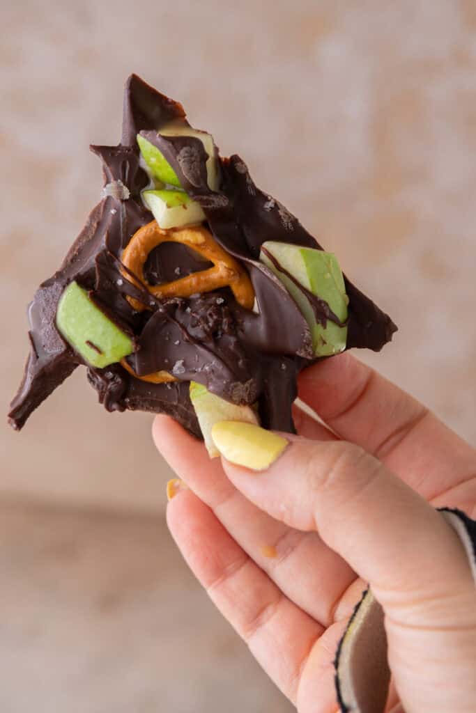 caramel apple bark recipe being held up by a hand