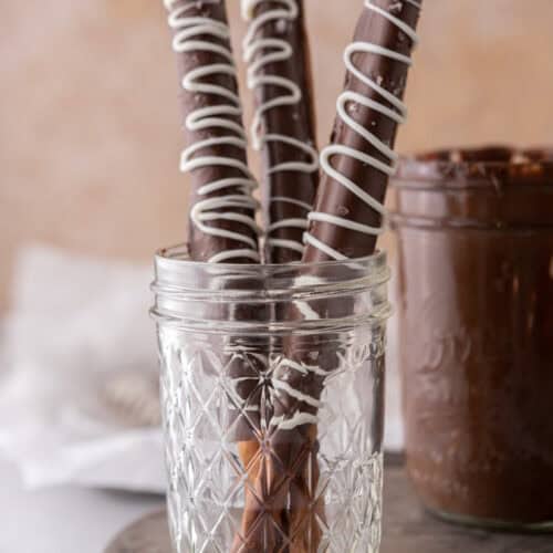 three caramel chocolate covered pretzel rods in a cup