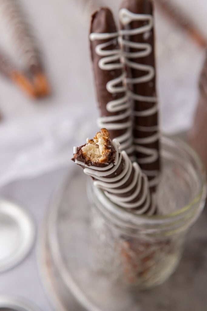 close up of three caramel chocolate covered pretzel rods in a cup