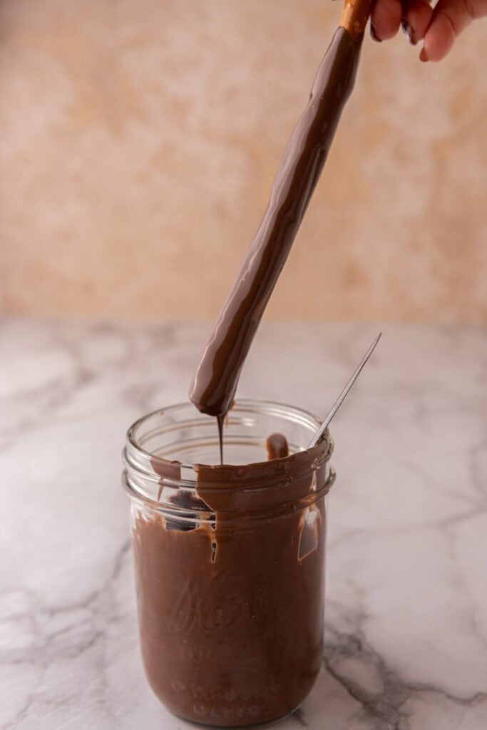 stick being dipped into the melted candy