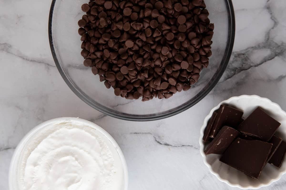 Ingredients for cool whip candy including whipped topping, milk chocolate chips, and dark chocolate.
