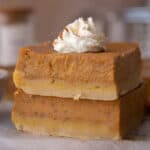 Creamy pumpkin pie bars with shortbread crust sliced into squares and topped with whipped cream.