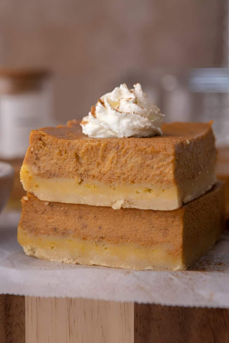 Creamy pumpkin pie bars with shortbread crust sliced into squares and topped with whipped cream.
