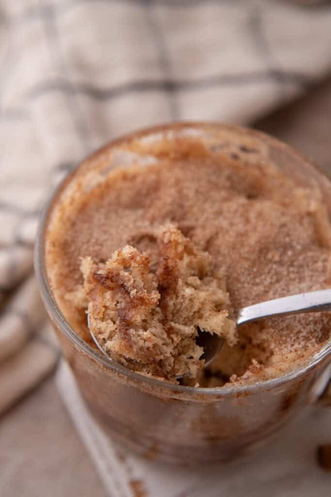 snickerdoodle mug cake recipe in a cup getting scooped