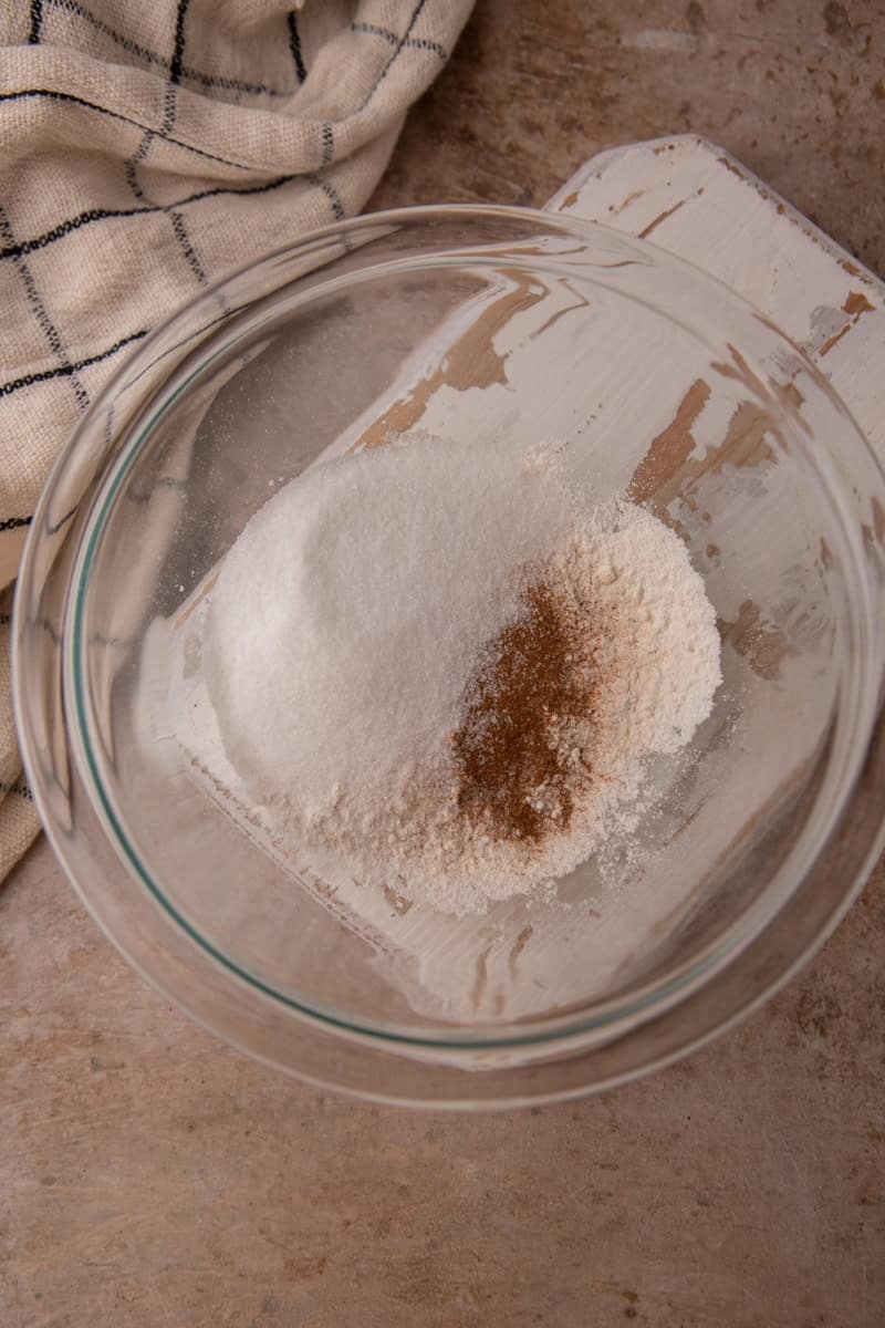 Flour, sugar, cinnamon, and baking powder in a glass bowl before whisking.