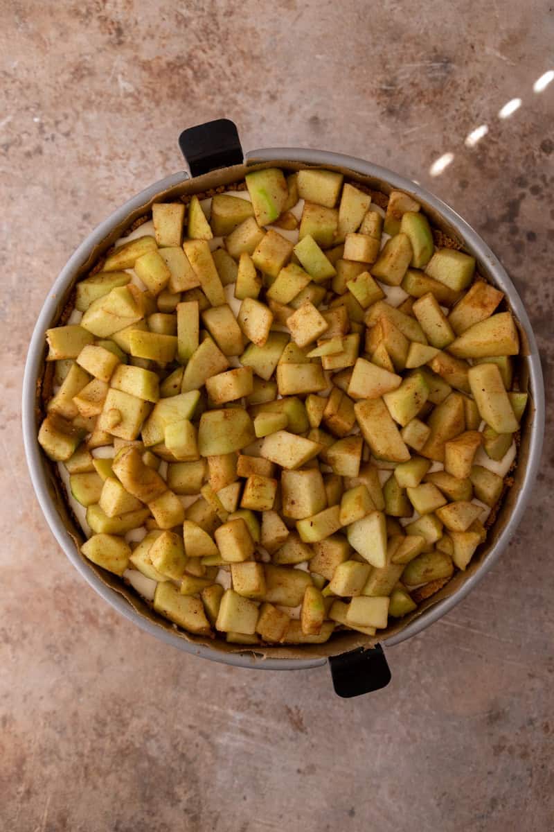 Cinnamon-spiced diced apples layered over the cheesecake filling in the springform pan.