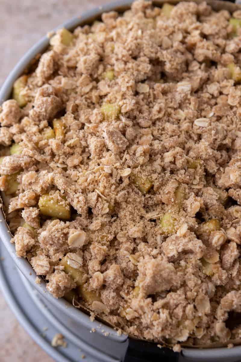 Baked apple crisp cheesecake with golden oat streusel topping in the springform pan.