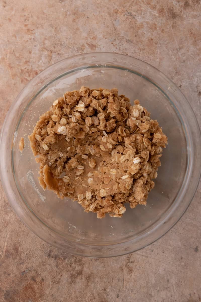 Oat streusel topping mixed with melted butter into buttery clumps in a glass bowl.