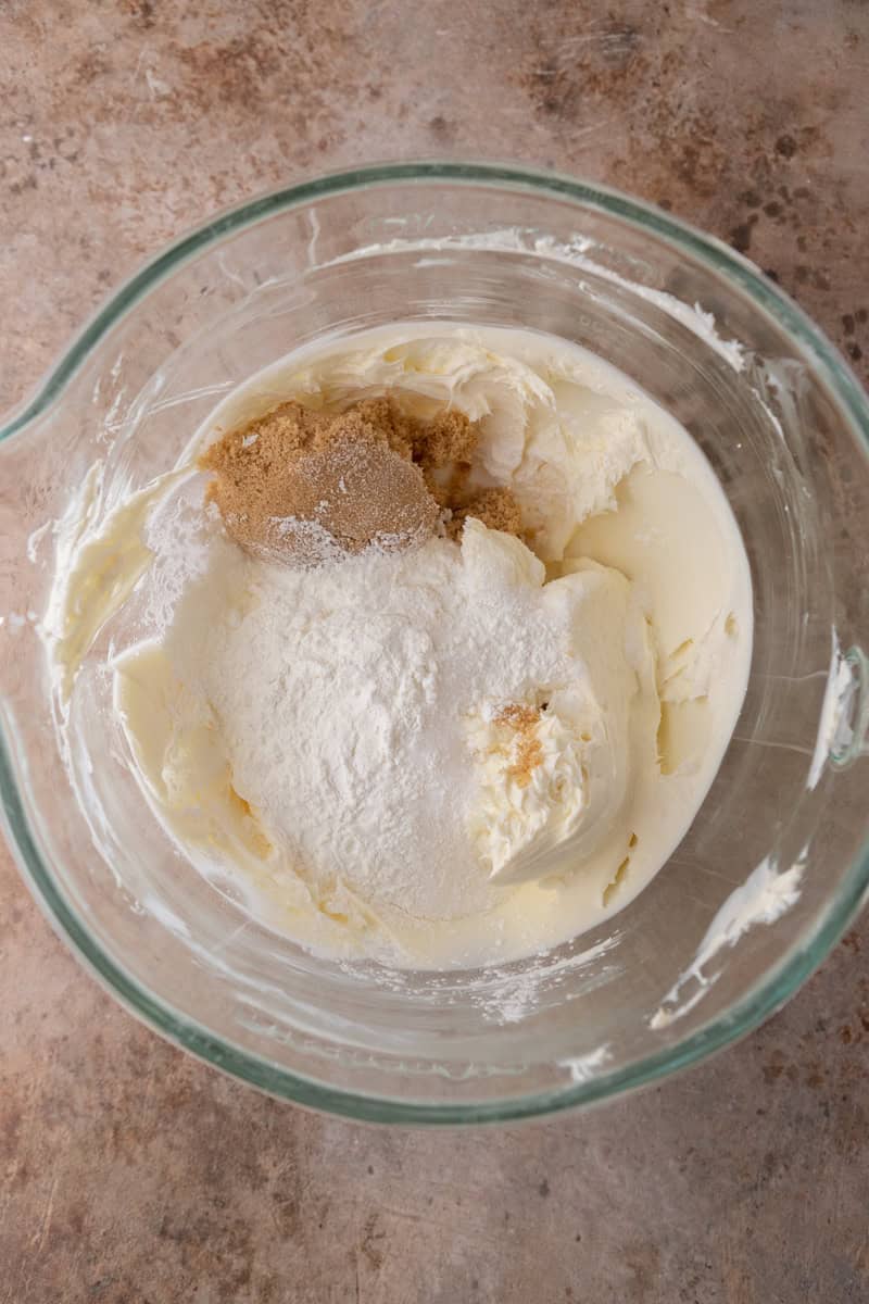Softened cream cheese topped with brown sugar and cornstarch in a mixing bowl.