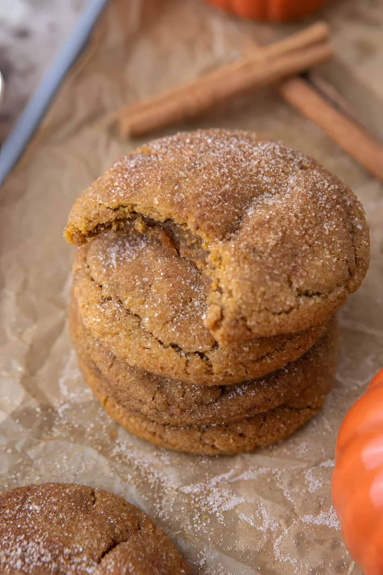 Stack of chewy brown butter pumpkin snickerdoodles with crackled cinnamon sugar tops on parchment paper.