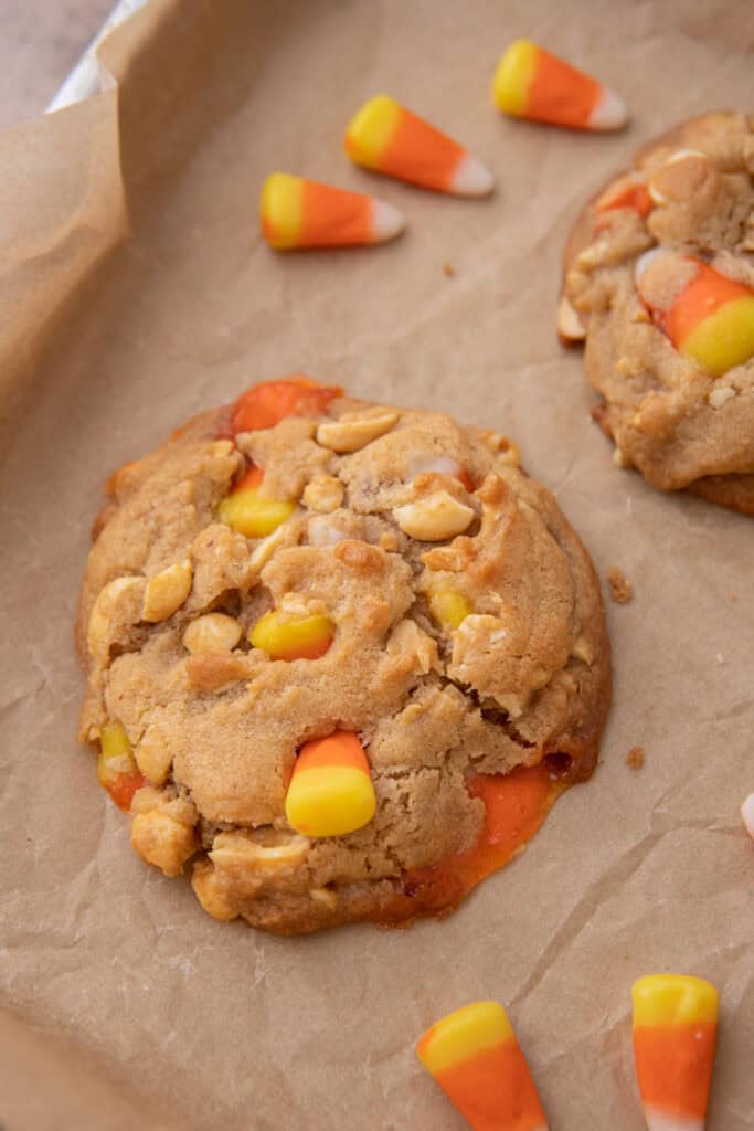 Baked candy corn cookies with golden edges cooling on a silicone mat in a sheet pan.