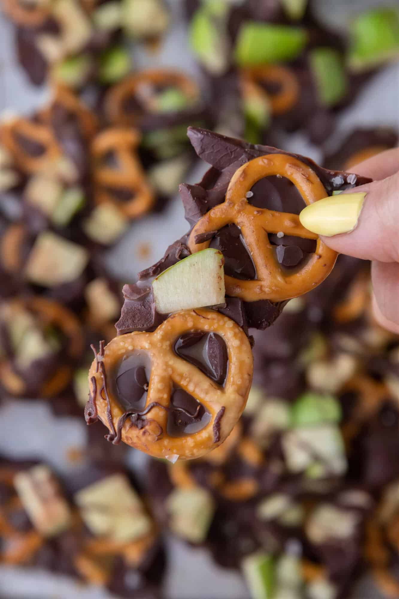 caramel apple bark recipe being held up by a hand.