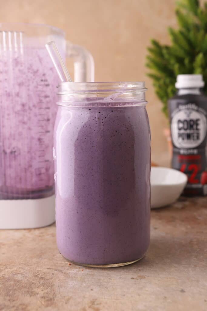 side shot of Blueberry protein shake recipe in a cup with a straw