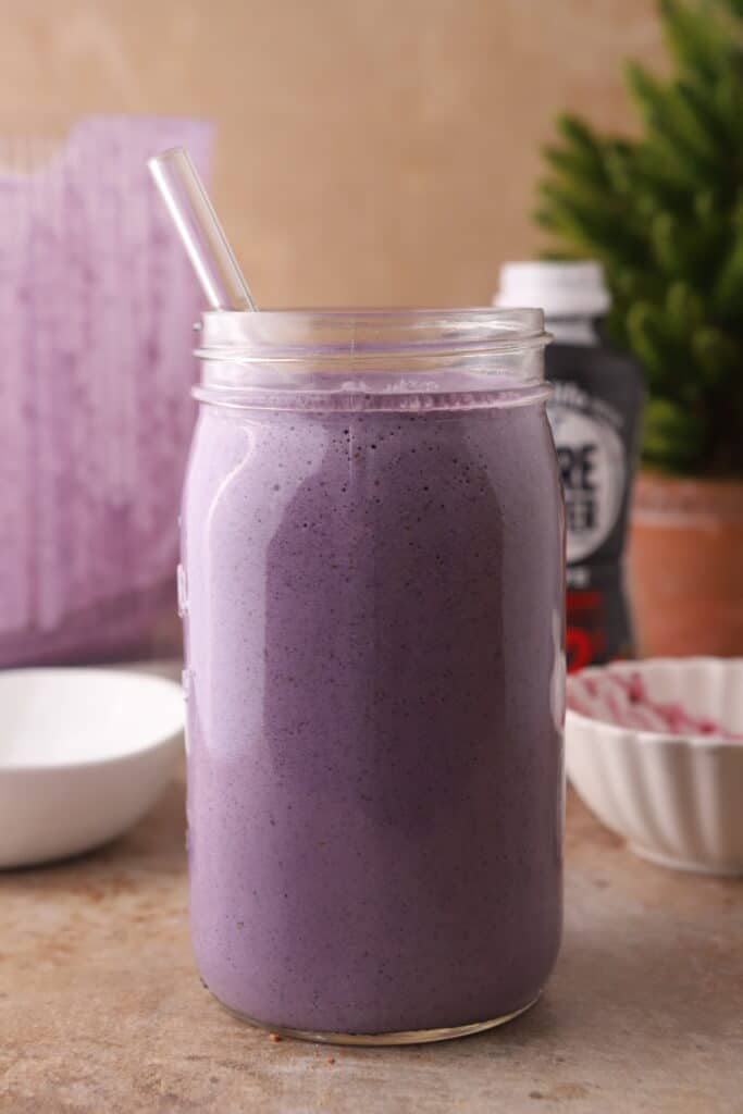 side shot of Blueberry protein shake recipe in a cup with a straw