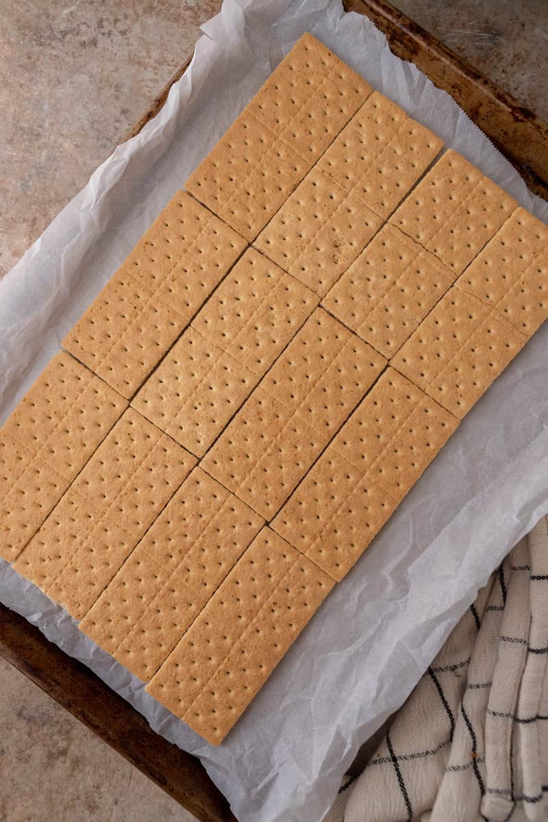 Graham cracker sheets arranged in a single layer on a lined baking sheet for pecan pie bark.