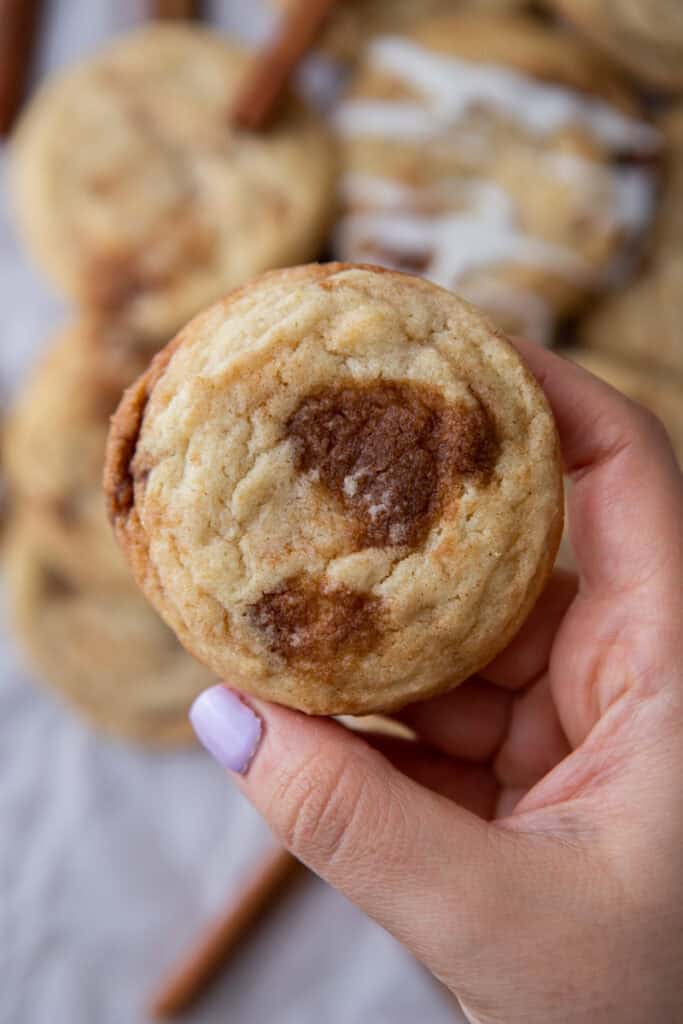 cinnamon roll sugar cookie being held up by a hand