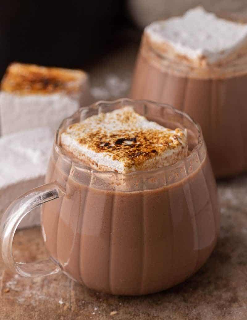 Close-up of slow cooker hot chocolate in a glass mug topped with toasted marshmallow.