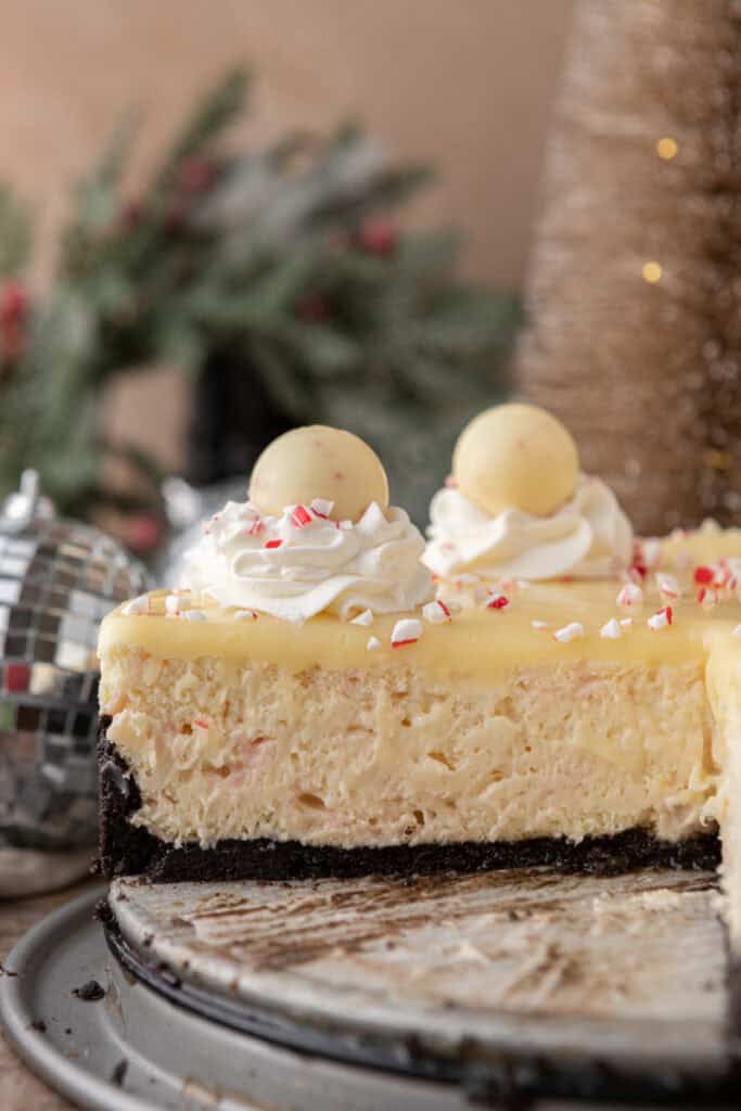 Close-up of the peppermint cheesecake showing the creamy interior, Oreo crust, white chocolate ganache, whipped cream swirls, and peppermint truffles.